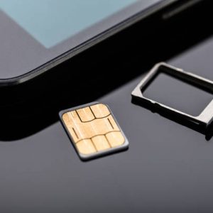 Close-up Of Nano Sim Card Ready To Insert In Smart Phone Over The Desk